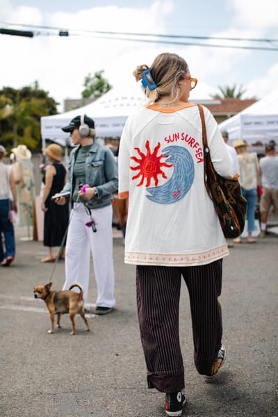 A shopper walking the outdoor aisle between white Mermade tents