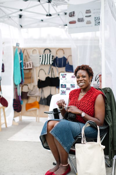 A maker crocheting in her own tent, her bags hung behind her